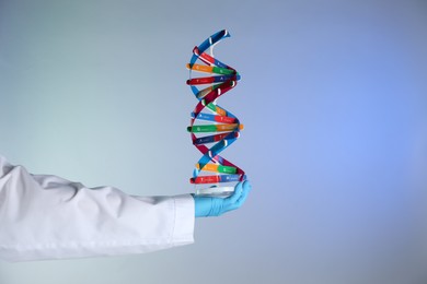 Photo of Scientist with DNA structure model on color background, closeup