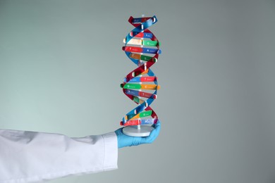 Photo of Scientist with DNA structure model on color background, closeup