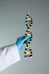 Photo of Scientist with DNA structure model on color background, closeup