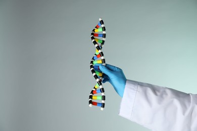 Photo of Scientist with DNA structure model on color background, closeup