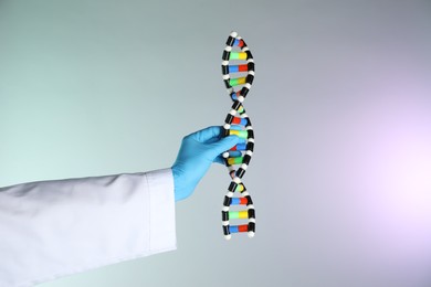 Photo of Scientist with DNA structure model on color background, closeup