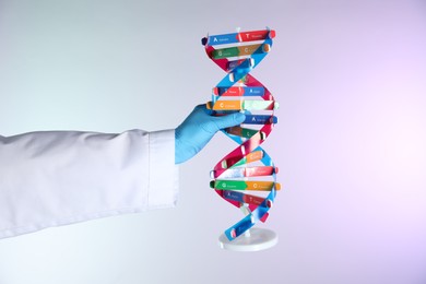 Photo of Scientist with DNA structure model on color background, closeup