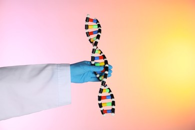 Photo of Scientist with DNA structure model on color background, closeup