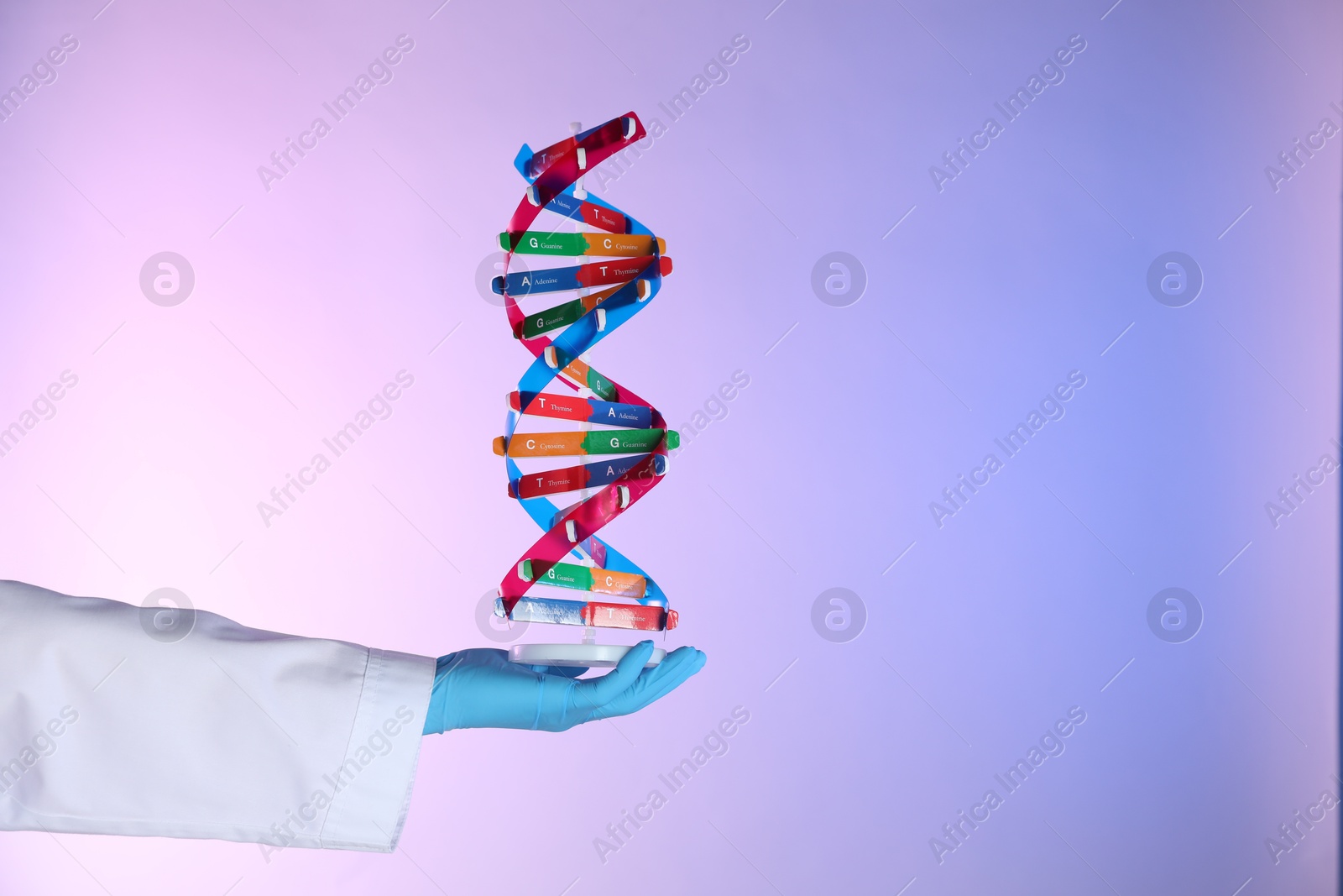 Photo of Scientist with DNA structure model on color background, closeup