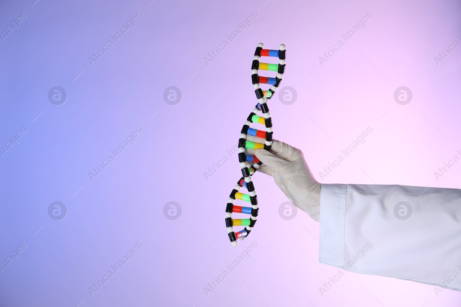 Photo of Scientist with DNA structure model on color background, closeup