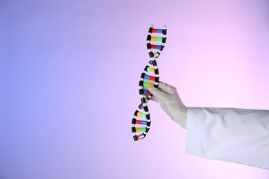 Photo of Scientist with DNA structure model on color background, closeup