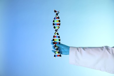 Photo of Scientist with DNA structure model on color background, closeup