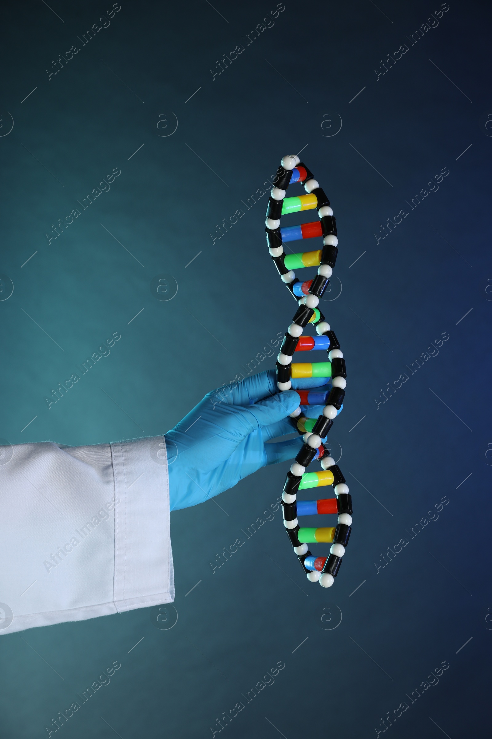 Photo of Scientist with DNA structure model on dark blue background, closeup