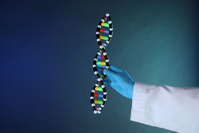 Photo of Scientist with DNA structure model on dark blue background, closeup