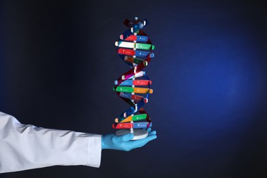 Photo of Scientist with DNA structure model on dark blue background, closeup