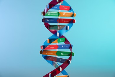 Photo of DNA structure model on light blue background, closeup