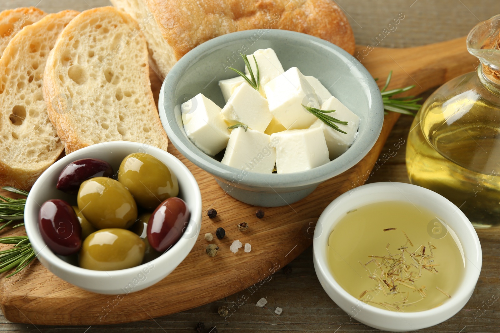 Photo of Delicious marinated olives, bread and feta cheese served on wooden table, closeup