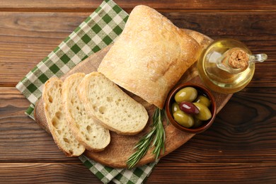 Photo of Delicious marinated olives, bread and feta cheese served on wooden table, top view