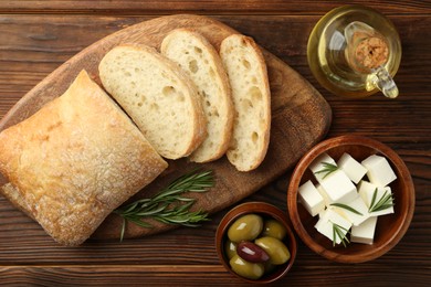 Photo of Delicious marinated olives, bread and feta cheese served on wooden table, flat lay