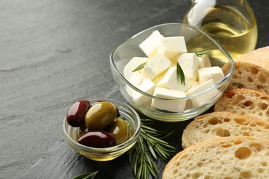 Photo of Delicious marinated olives, bread and feta cheese served on black table, closeup. Space for text