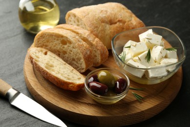 Photo of Delicious marinated olives, bread and feta cheese served on black table, closeup