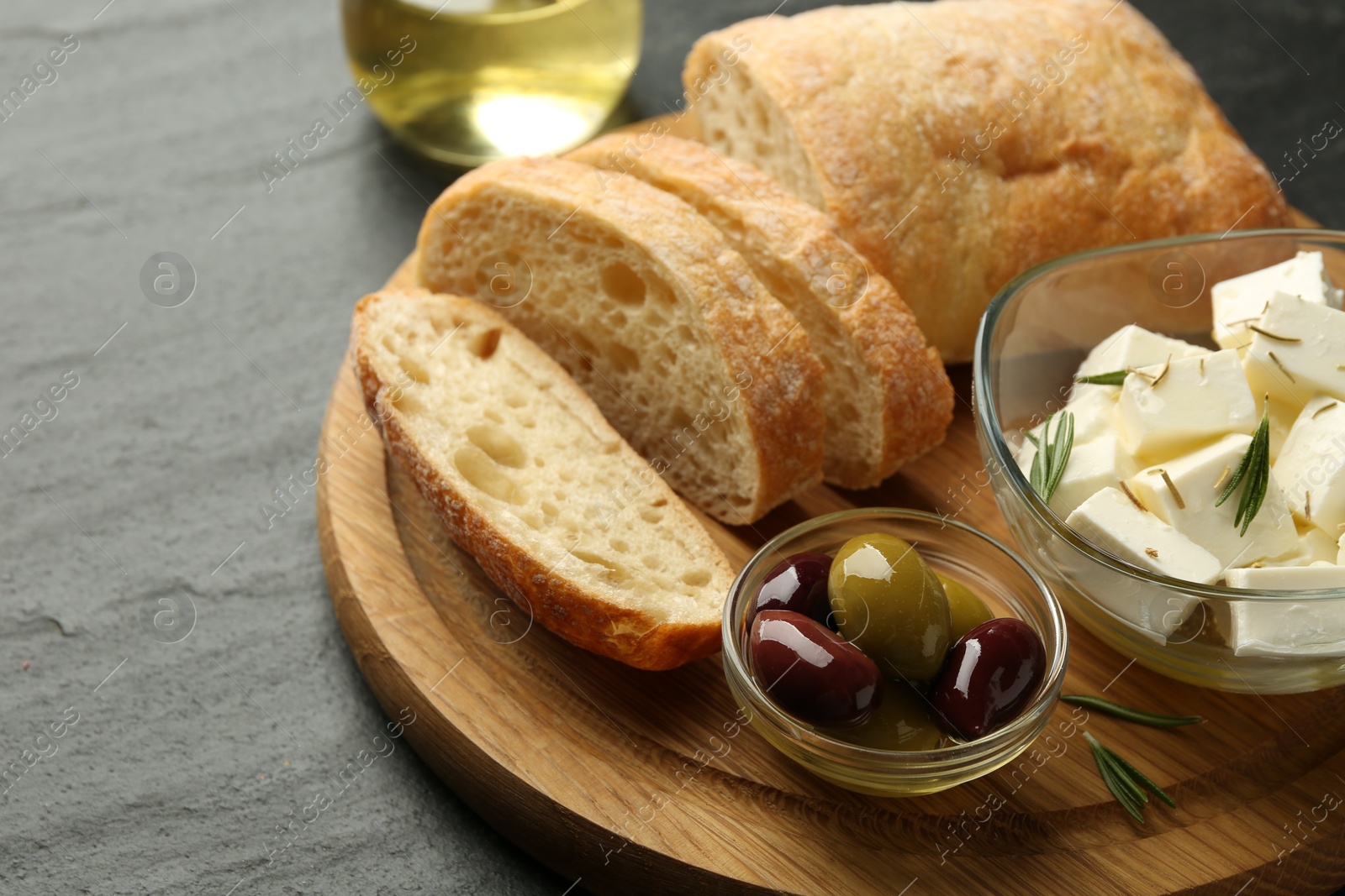 Photo of Delicious marinated olives, bread and feta cheese served on black table, closeup