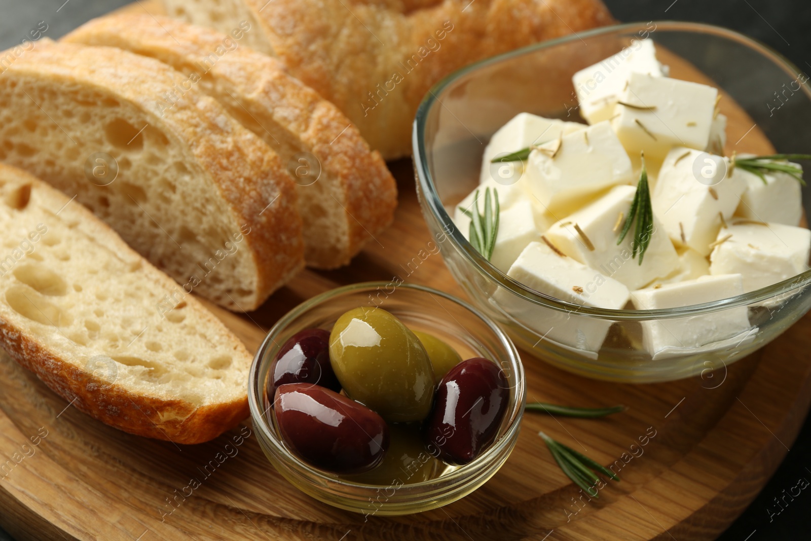 Photo of Delicious marinated olives, bread and feta cheese served on table, closeup