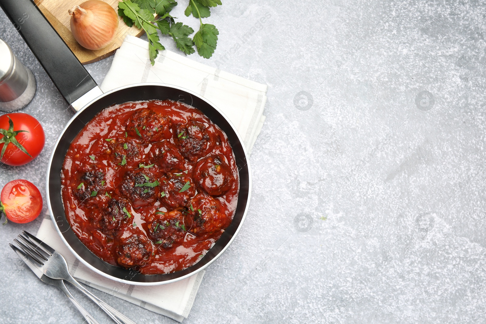 Photo of Delicious meatballs with tomato sauce and herbs in served on grey table, flat lay. Space for text