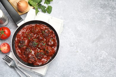 Photo of Delicious meatballs with tomato sauce and herbs in served on grey table, flat lay. Space for text