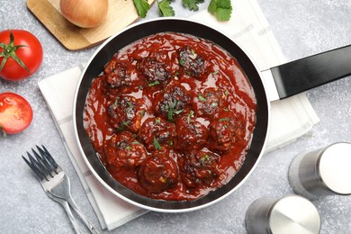 Photo of Delicious meatballs with tomato sauce and herbs in served on grey table, flat lay