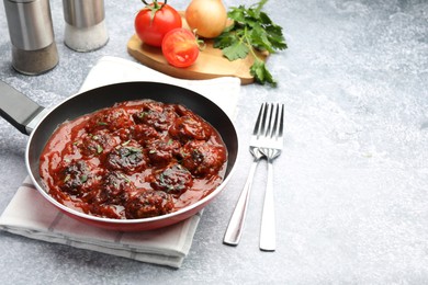 Photo of Delicious meatballs with tomato sauce and herbs in served on grey table