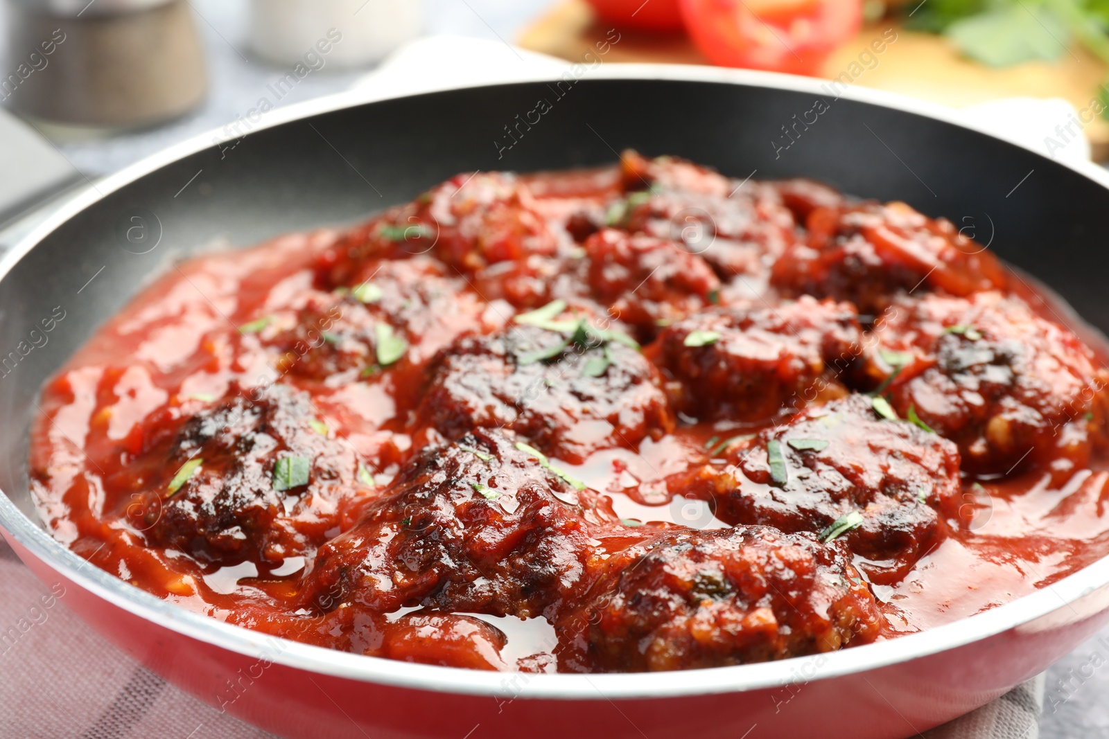 Photo of Delicious meatballs with tomato sauce and herbs in on table, closeup