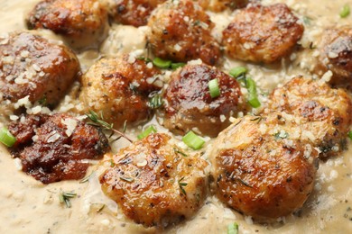 Photo of Delicious meatballs with gravy cream sauce and herbs, closeup