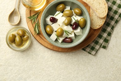 Photo of Tasty olives served with feta cheese, bread and oil on table, flat lay. Space for text