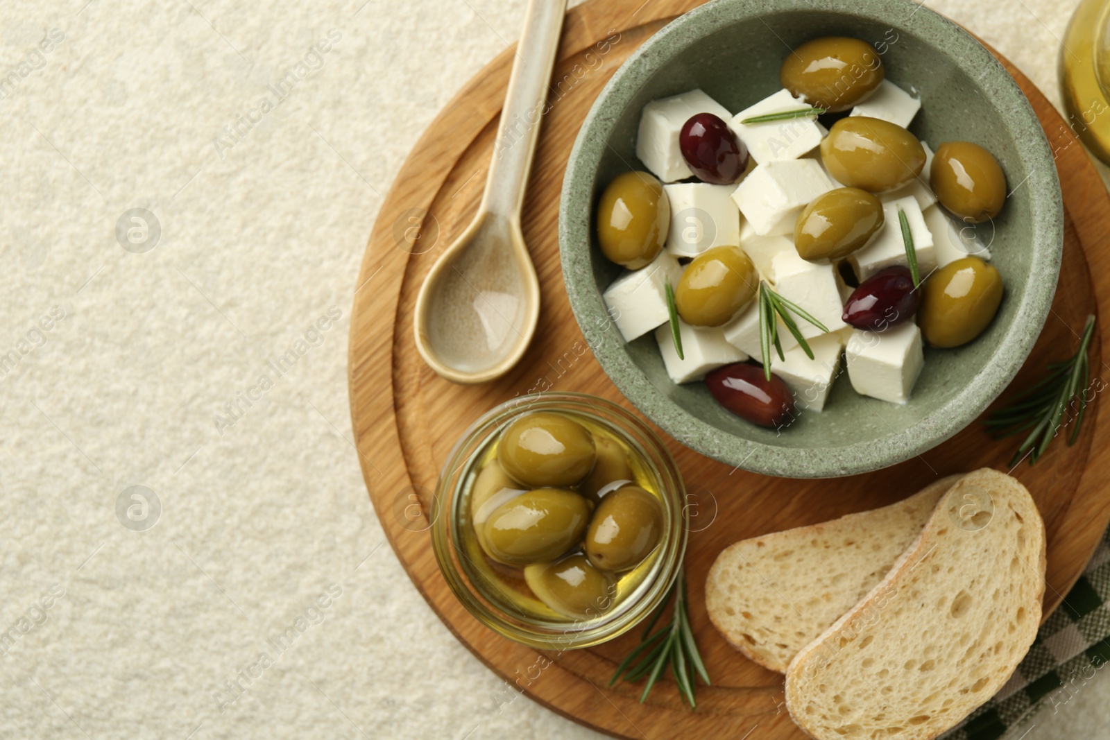 Photo of Tasty olives served with feta cheese and bread on table, flat lay. Space for text