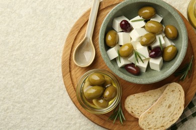 Photo of Tasty olives served with feta cheese and bread on table, flat lay. Space for text