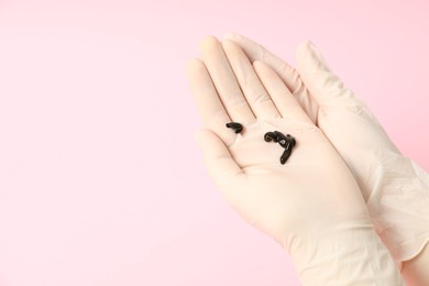 Photo of Woman holding medicinal leeches on pink background, closeup. Space for text