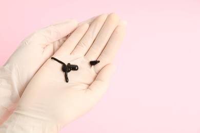 Photo of Woman holding medicinal leeches on pink background, closeup. Space for text