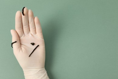 Photo of Woman holding medicinal leeches on green background, closeup. Space for text