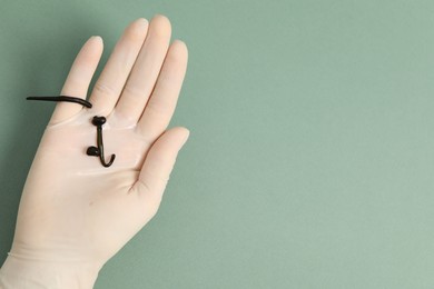 Photo of Woman holding medicinal leeches on green background, closeup. Space for text