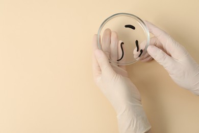 Photo of Woman holding Petri dish with medicinal leeches on pale yellow background, top view. Space for text