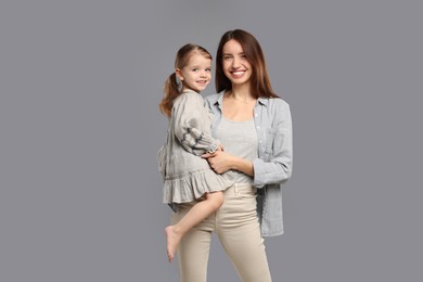 Photo of Portrait of happy mother with her cute little daughter on grey background