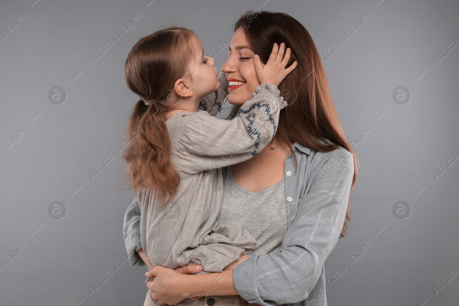 Photo of Happy mother with her cute little daughter on grey background