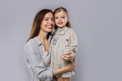 Photo of Portrait of happy mother with her cute little daughter on grey background