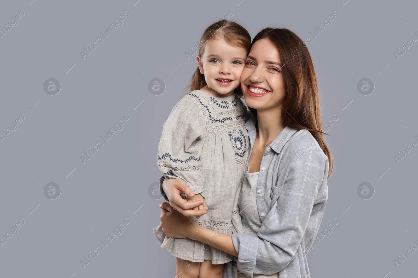 Photo of Portrait of happy mother with her cute little daughter on grey background