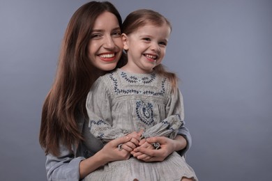 Portrait of happy mother with her cute little daughter on grey background