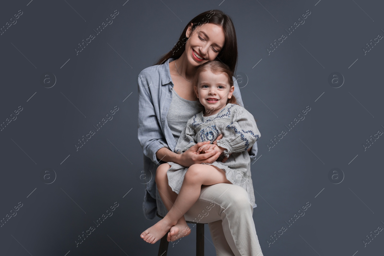 Photo of Happy mother with her cute little daughter on grey background