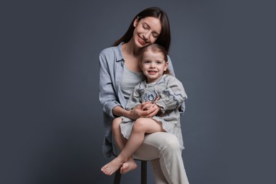 Photo of Happy mother with her cute little daughter on grey background