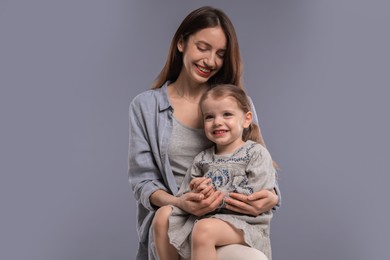 Photo of Happy mother with her cute little daughter on grey background