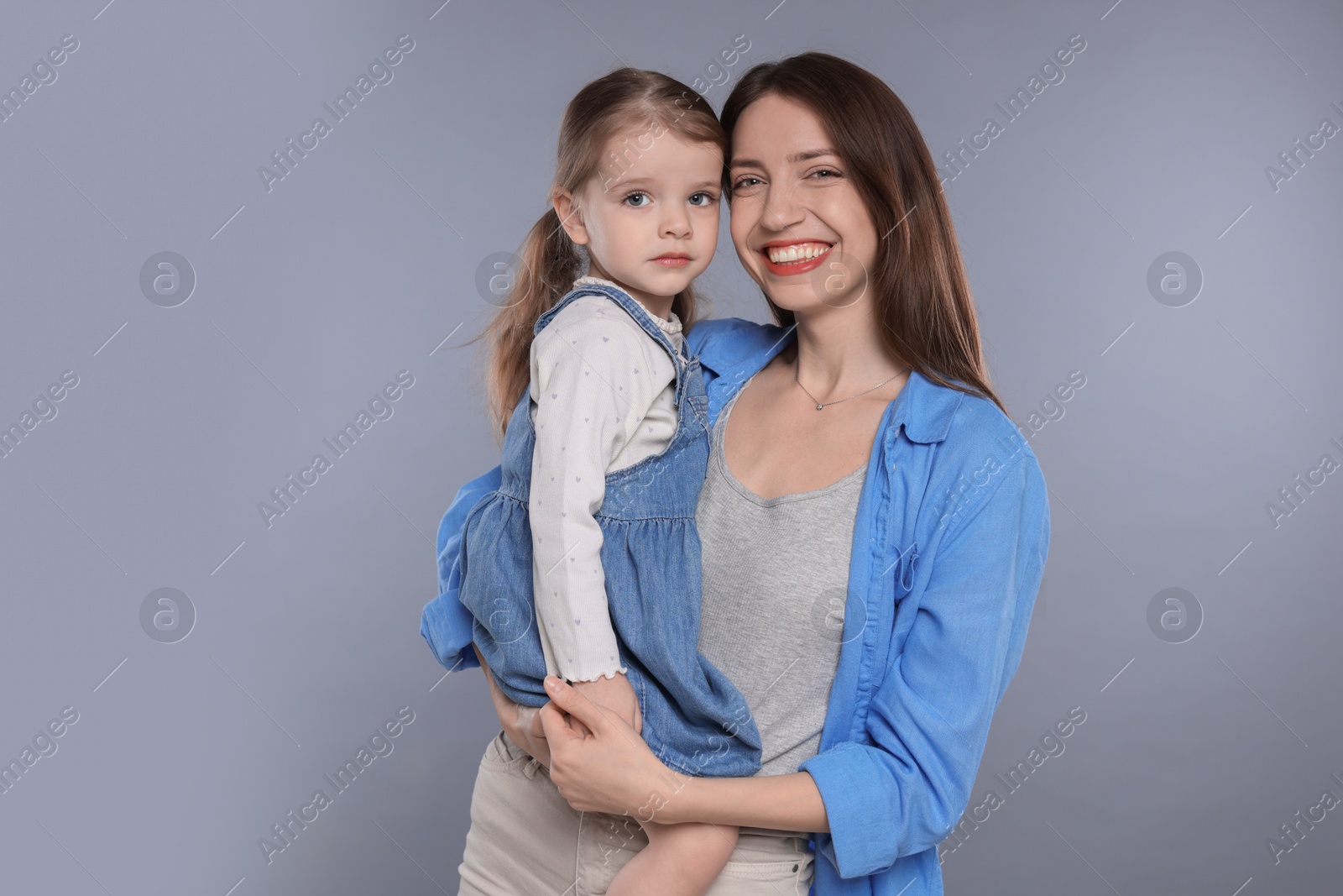 Photo of Portrait of happy mother with her cute little daughter on grey background