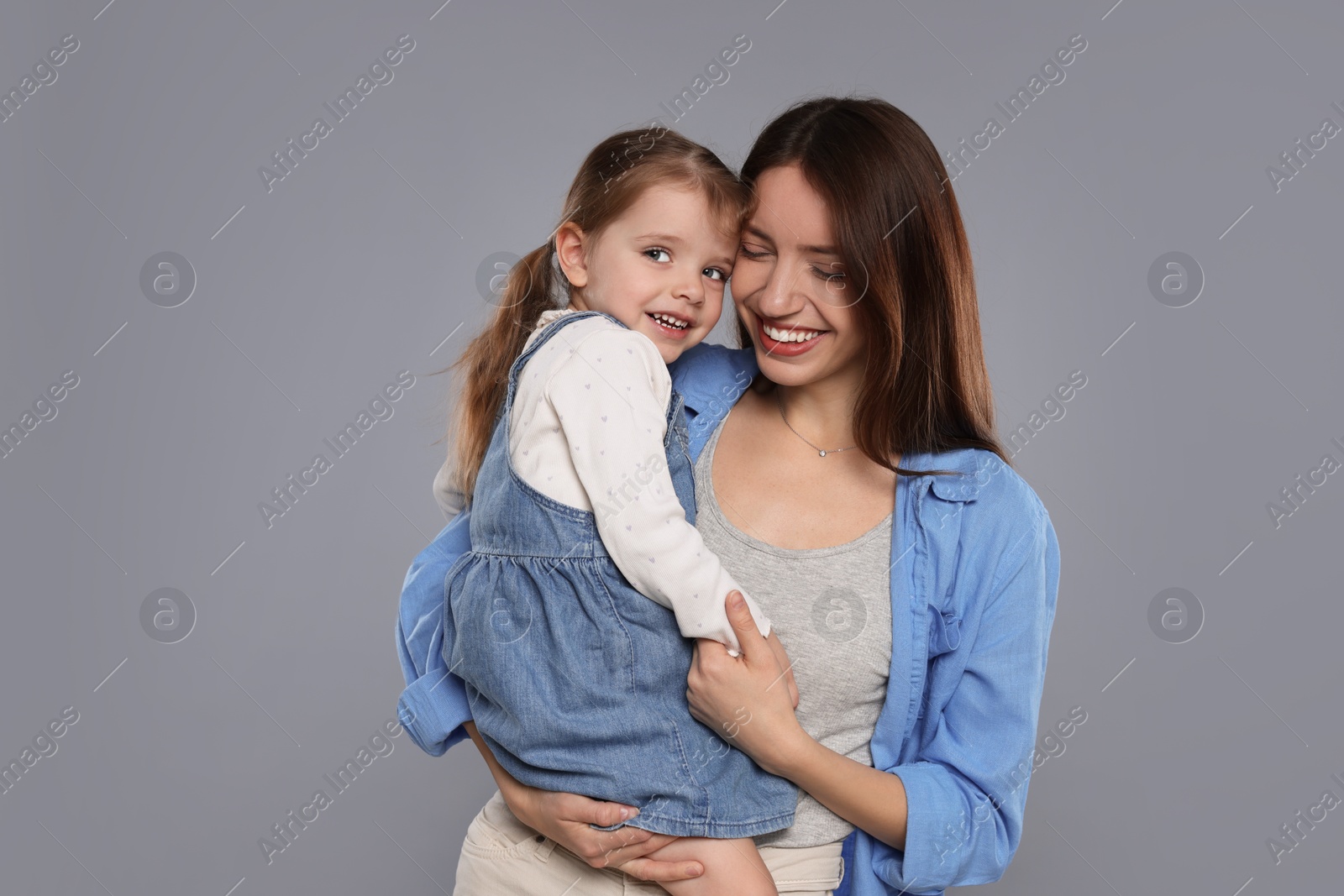 Photo of Happy mother with her cute little daughter on grey background