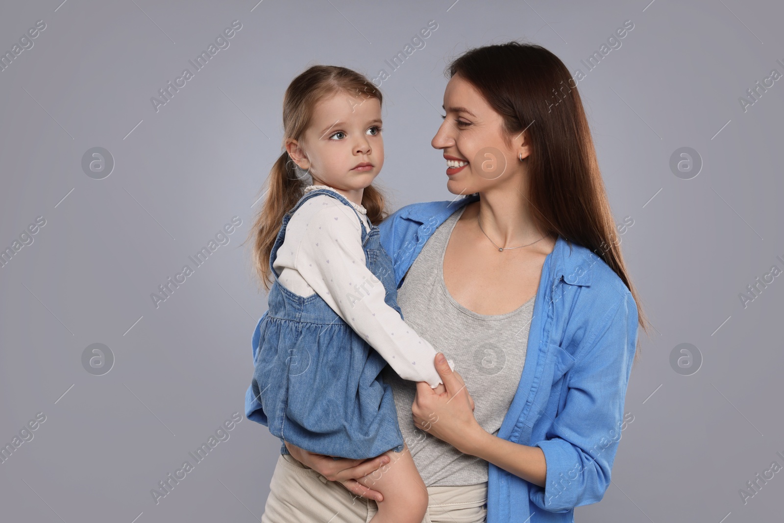 Photo of Happy mother with her cute little daughter on grey background