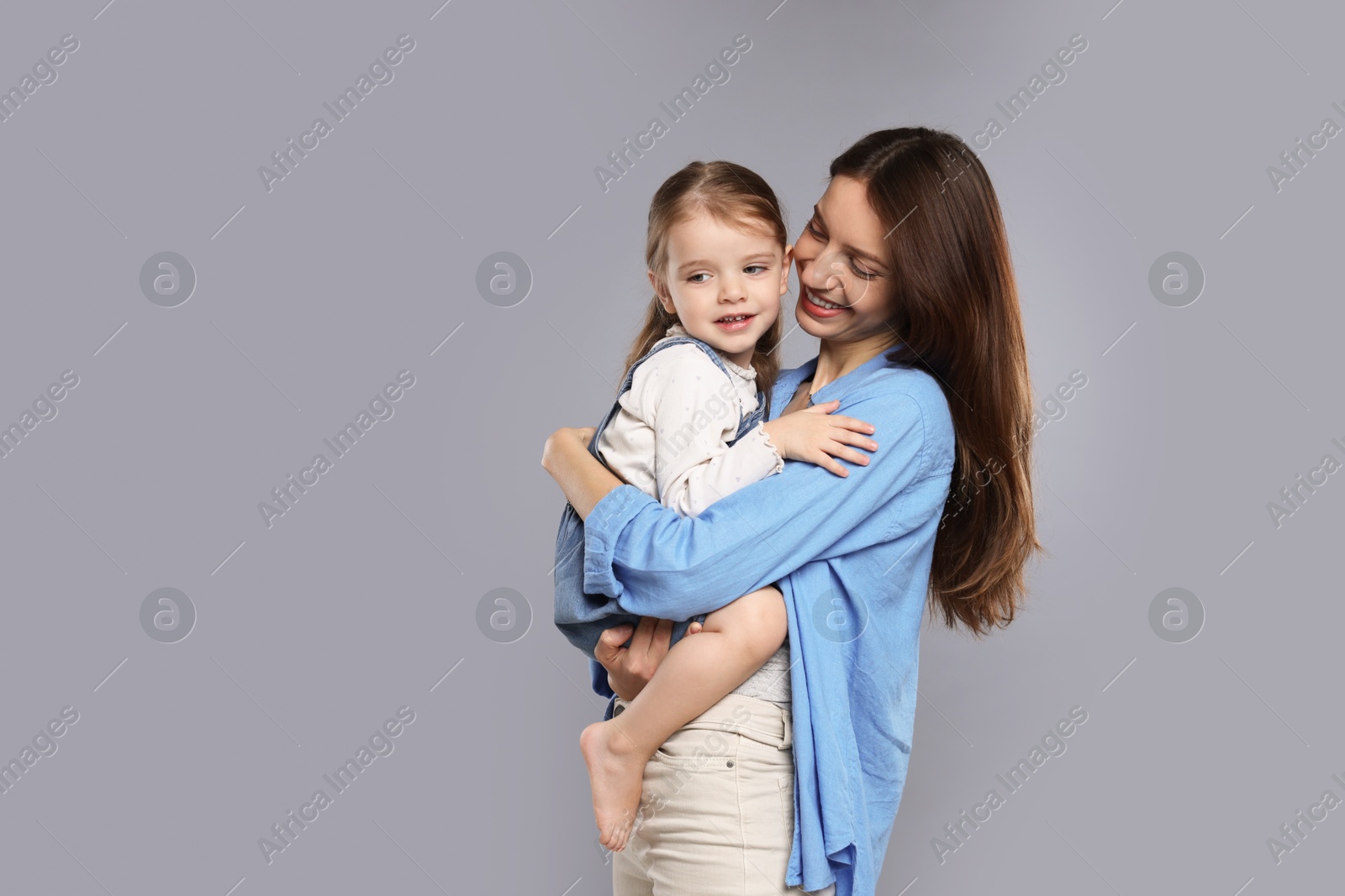 Photo of Happy mother with her cute little daughter on grey background, space for text