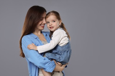 Photo of Happy mother with her cute little daughter on grey background, space for text