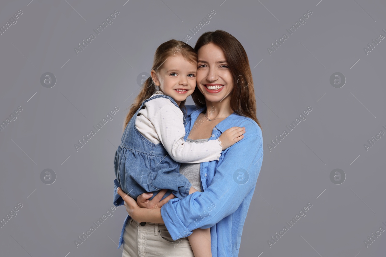 Photo of Portrait of happy mother with her cute little daughter on grey background